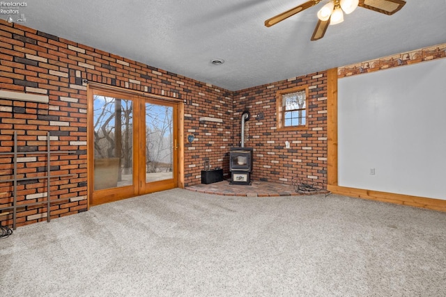 unfurnished living room featuring plenty of natural light, carpet floors, and brick wall