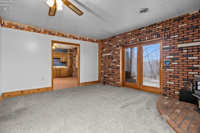 unfurnished living room featuring carpet floors, a textured ceiling, and brick wall