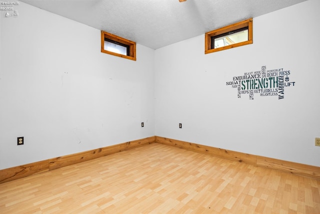 empty room featuring a textured ceiling, hardwood / wood-style flooring, and plenty of natural light