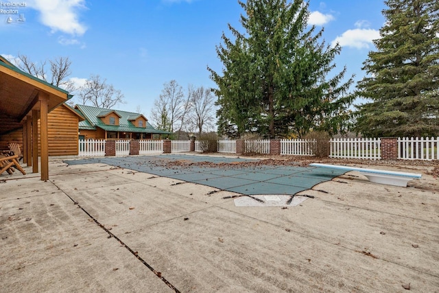 view of pool with a diving board and a patio