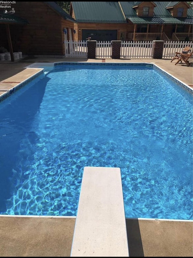 view of swimming pool with a patio and a diving board