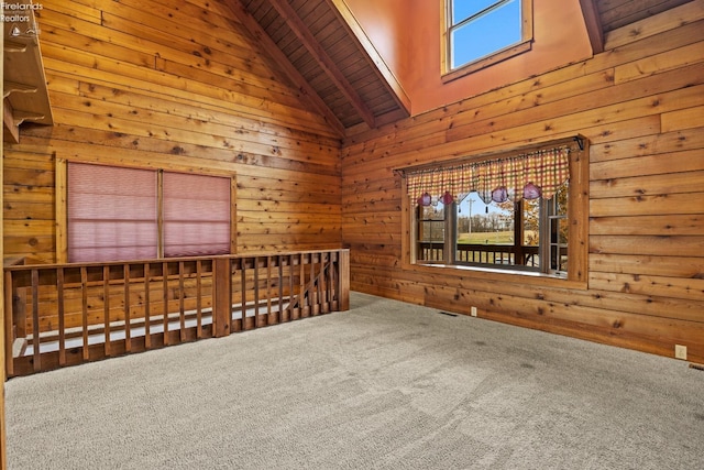 carpeted empty room featuring beamed ceiling, wood walls, wooden ceiling, and high vaulted ceiling