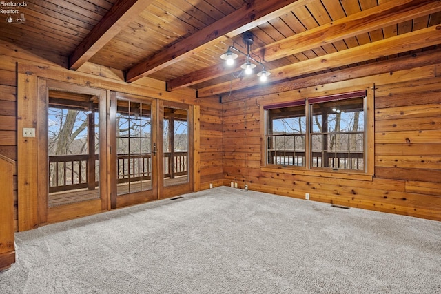 carpeted empty room featuring wood walls, plenty of natural light, beamed ceiling, and wood ceiling