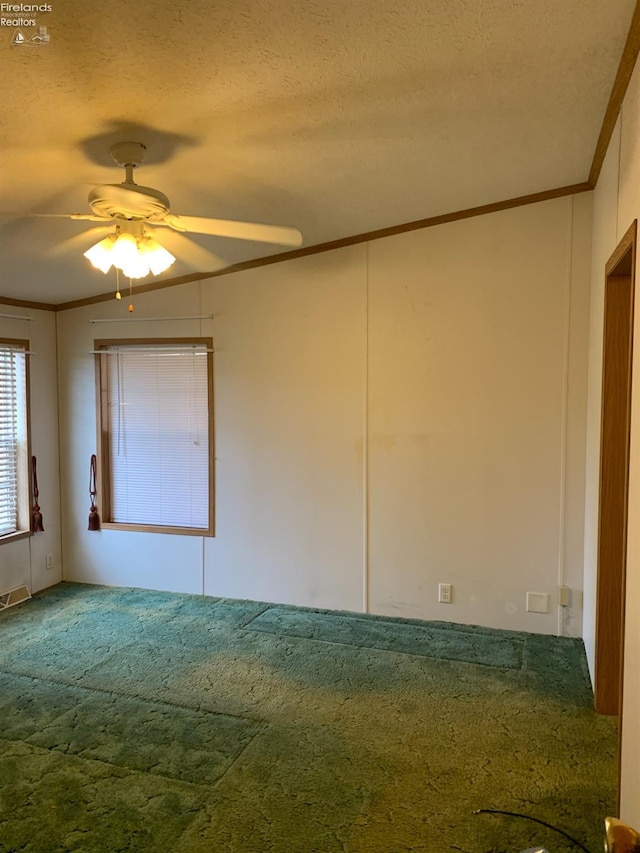 carpeted empty room featuring ceiling fan, crown molding, and a textured ceiling