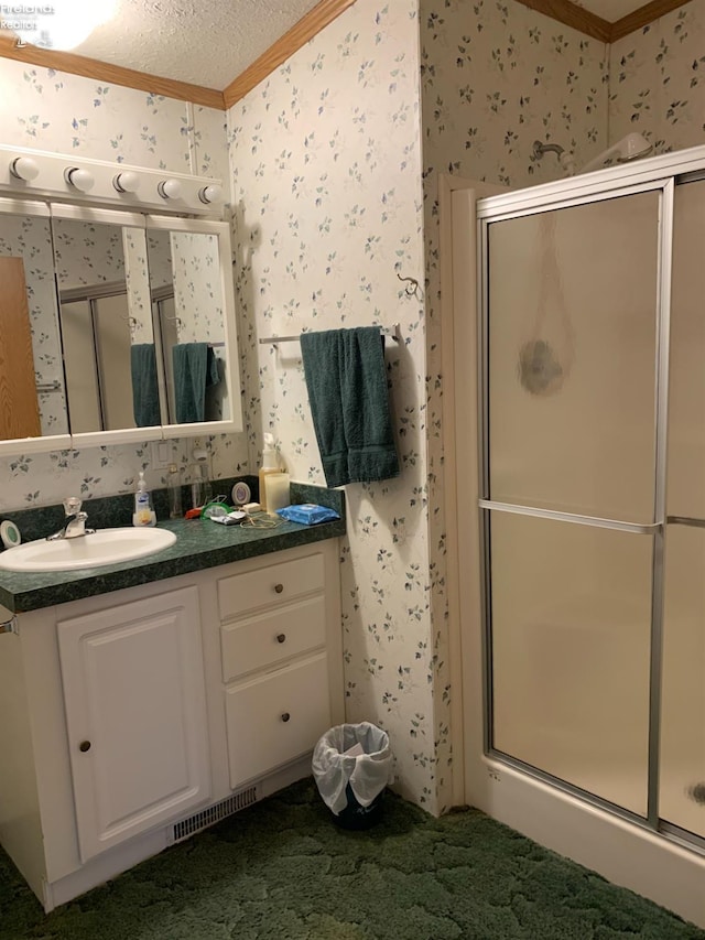 bathroom with a shower with door, a textured ceiling, and ornamental molding