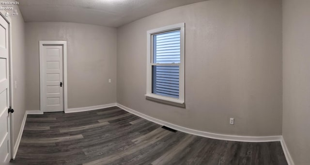 empty room featuring dark hardwood / wood-style floors and a textured ceiling