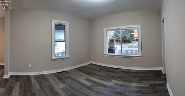 spare room featuring dark hardwood / wood-style flooring and plenty of natural light