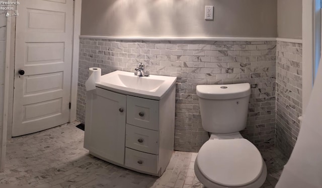 bathroom with vanity, tile walls, and toilet