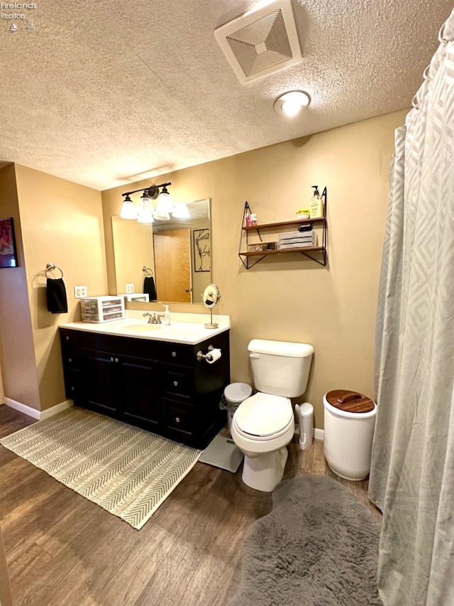 bathroom with vanity, toilet, wood-type flooring, and a textured ceiling