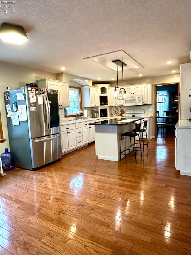 kitchen with stainless steel fridge, a breakfast bar, white cabinets, and pendant lighting