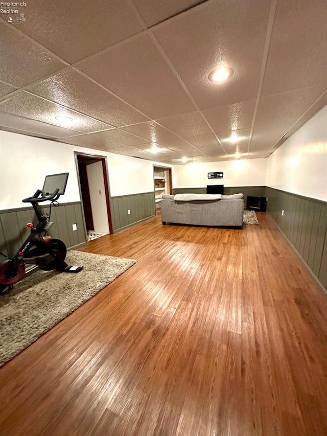 exercise room with a paneled ceiling and wood-type flooring