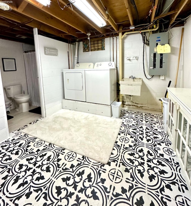 laundry area with electric panel, washer and clothes dryer, and sink