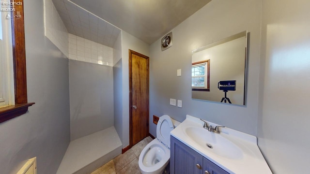 bathroom with tile patterned flooring, vanity, toilet, and walk in shower