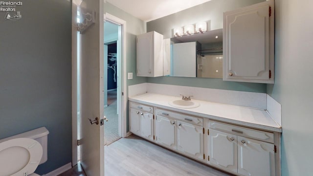 bathroom with hardwood / wood-style floors, vanity, and toilet