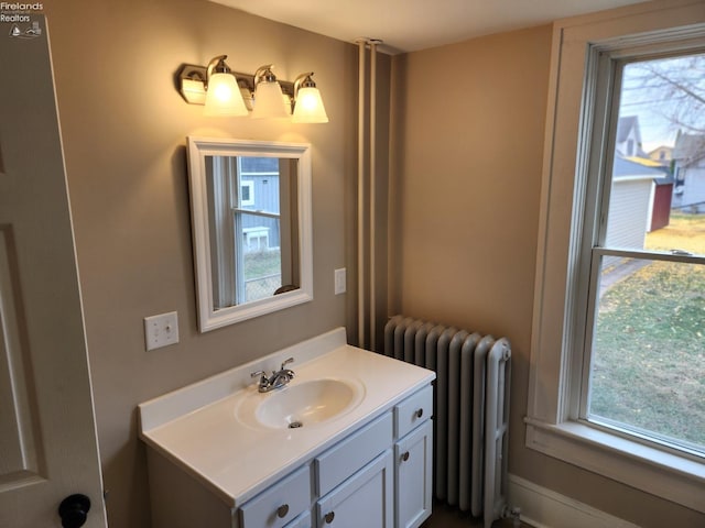 bathroom featuring radiator heating unit, vanity, and a healthy amount of sunlight