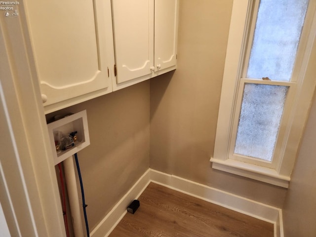 clothes washing area with cabinets, washer hookup, dark wood-type flooring, and a healthy amount of sunlight