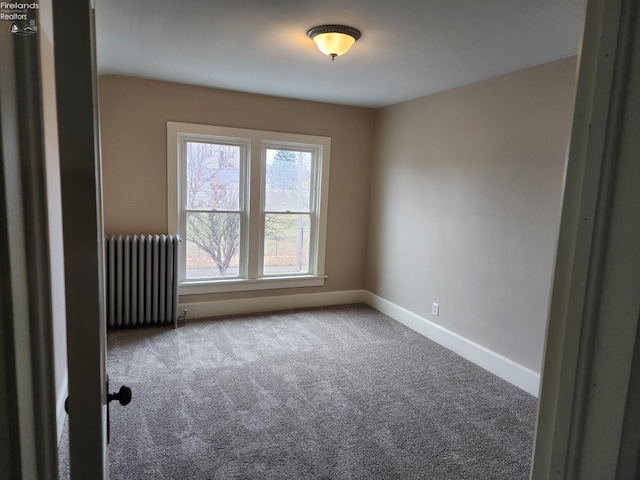 unfurnished room featuring radiator and carpet