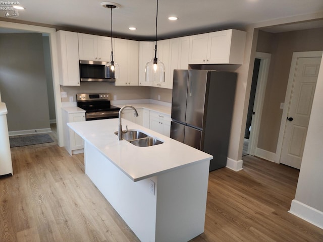 kitchen with decorative light fixtures, sink, white cabinetry, and stainless steel appliances