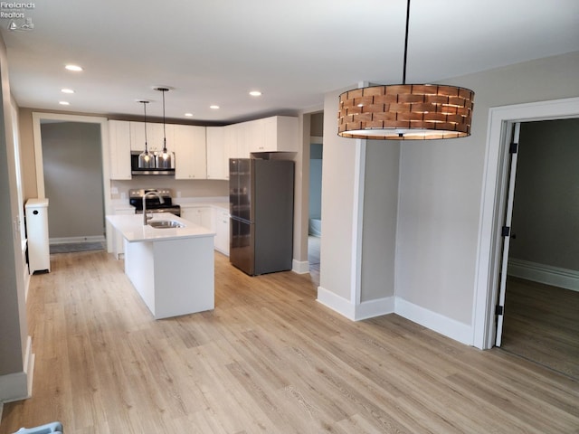 kitchen featuring stainless steel appliances, a kitchen island with sink, sink, pendant lighting, and light hardwood / wood-style floors