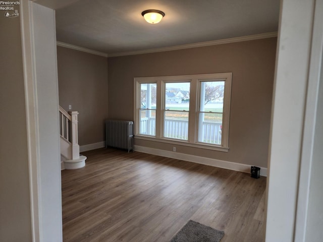 spare room with crown molding, radiator heating unit, and hardwood / wood-style floors