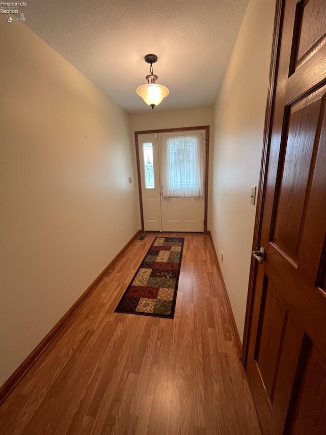 doorway featuring light hardwood / wood-style floors and a textured ceiling