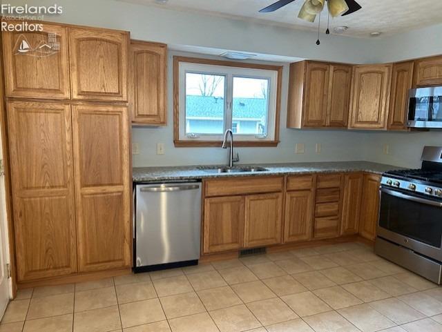 kitchen with light tile patterned flooring, appliances with stainless steel finishes, ceiling fan, and sink