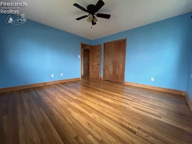 unfurnished bedroom with ceiling fan and wood-type flooring