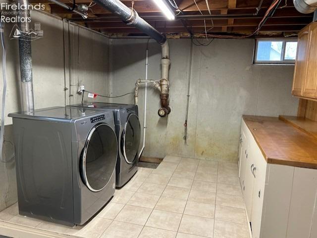 clothes washing area featuring light tile patterned floors, cabinets, and independent washer and dryer