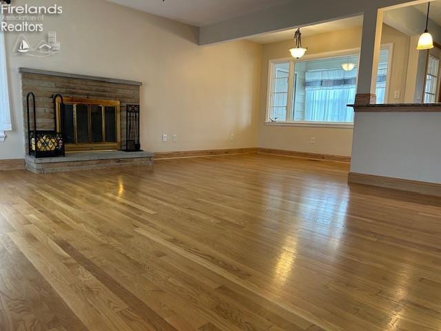 unfurnished living room with hardwood / wood-style flooring and a brick fireplace