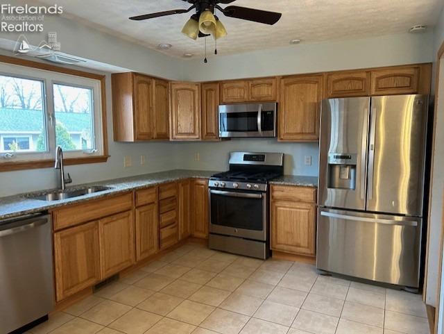 kitchen featuring ceiling fan, sink, a textured ceiling, light tile patterned floors, and appliances with stainless steel finishes