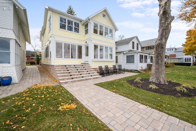 back of house with a sunroom, a yard, and a patio