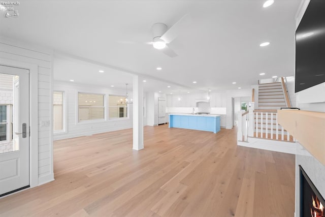 unfurnished living room with ceiling fan and light wood-type flooring