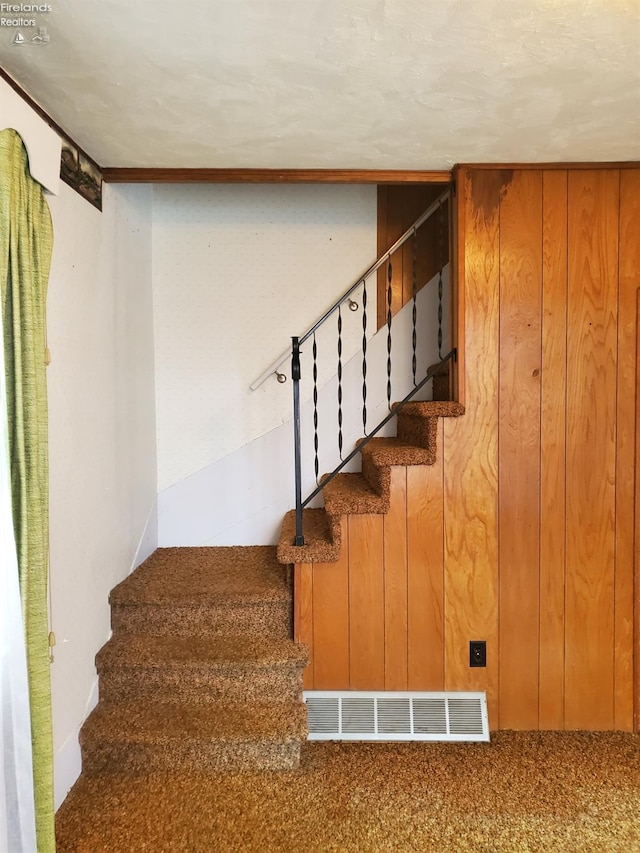 staircase featuring carpet and wood walls