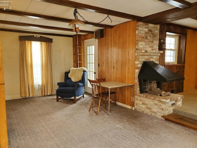 sitting room with beam ceiling, carpet floors, and wood walls