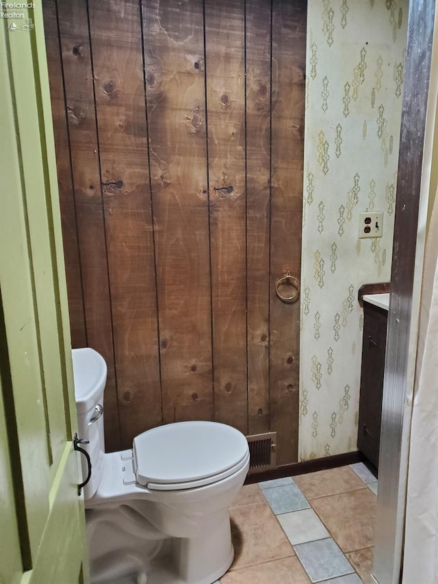 bathroom featuring toilet, tile patterned floors, and wood walls