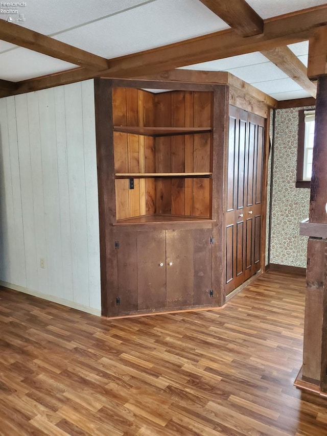 interior space with wooden walls, beamed ceiling, and wood-type flooring