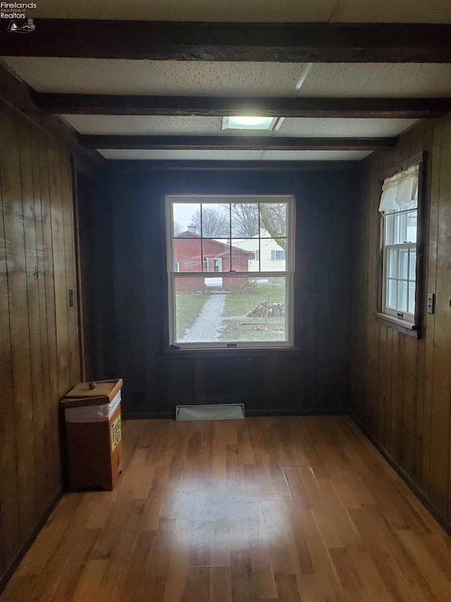 unfurnished room with hardwood / wood-style floors, beam ceiling, and wooden walls