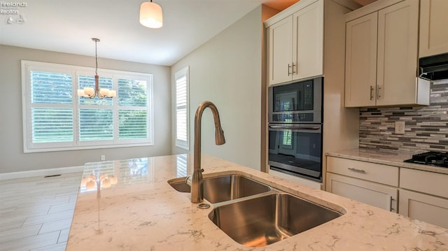 kitchen with backsplash, light stone counters, sink, and oven