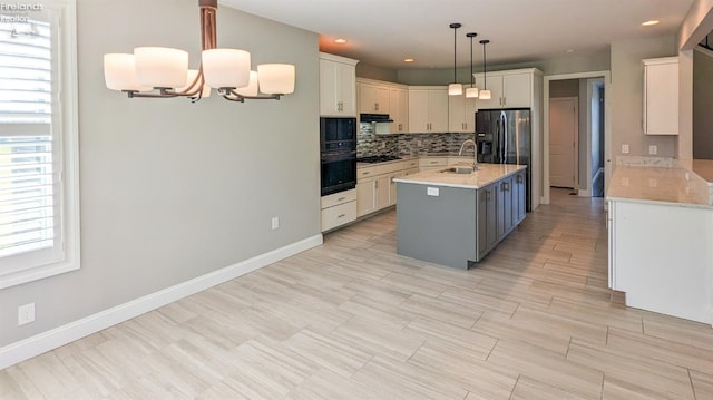 kitchen featuring white cabinets, a center island with sink, and hanging light fixtures