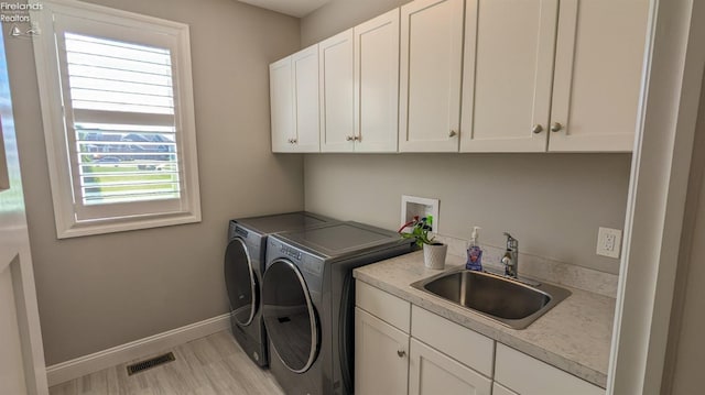 laundry area with plenty of natural light, cabinets, separate washer and dryer, and sink