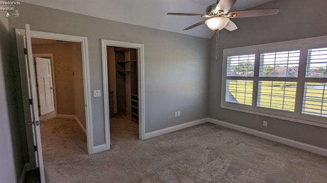 unfurnished bedroom featuring a closet, light colored carpet, a spacious closet, and ceiling fan