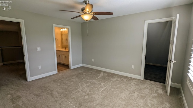 unfurnished bedroom with ensuite bathroom, ceiling fan, a walk in closet, and light carpet