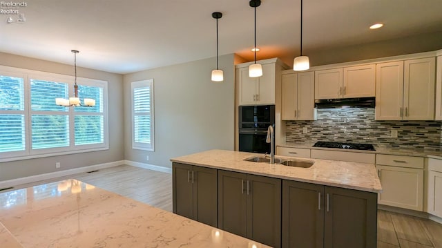 kitchen featuring black appliances, light hardwood / wood-style floors, light stone counters, and hanging light fixtures