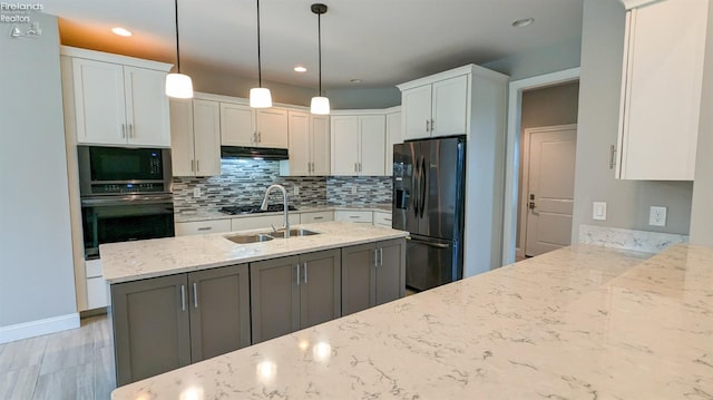 kitchen featuring sink, light stone countertops, decorative light fixtures, white cabinetry, and stainless steel appliances