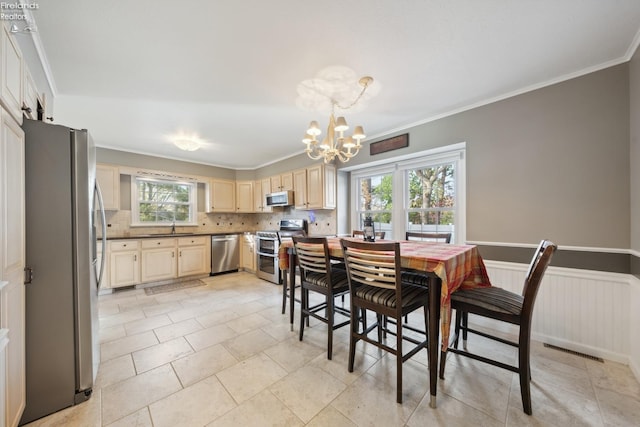 dining space featuring ornamental molding, sink, light tile patterned floors, and a chandelier