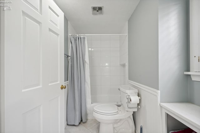 bathroom featuring tile patterned flooring, shower / bath combination with curtain, and toilet