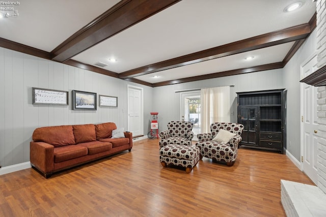 living room with hardwood / wood-style floors, beam ceiling, ornamental molding, and wooden walls