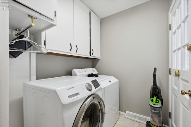 laundry area featuring washing machine and clothes dryer, light tile patterned floors, and cabinets