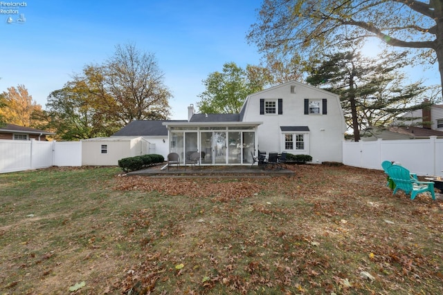 rear view of property featuring a lawn and a sunroom