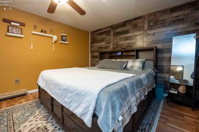 bedroom featuring wooden walls, hardwood / wood-style floors, and ceiling fan